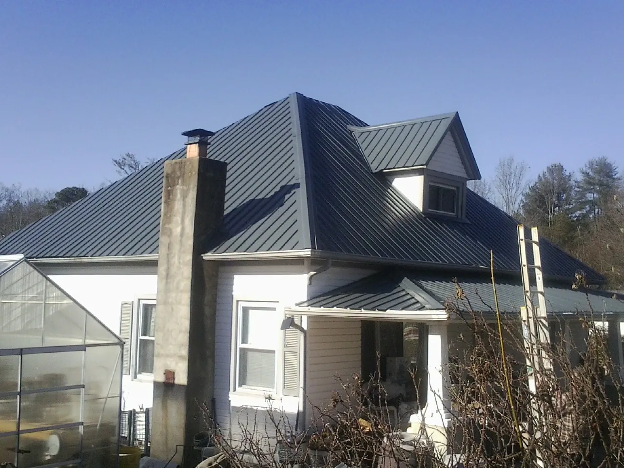 Dark blue standing seam metal roof on a white farmhouse with dormer — Slate & Tile Roof Repair by Roofing Brothers in Oregonia