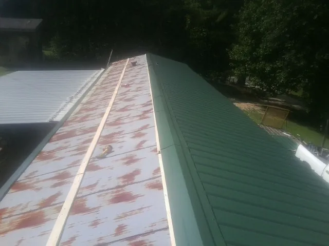Old rusted panels beside newly installed green metal roofing — Wind Damage Roof Repair by Roofing Brothers in Oregonia