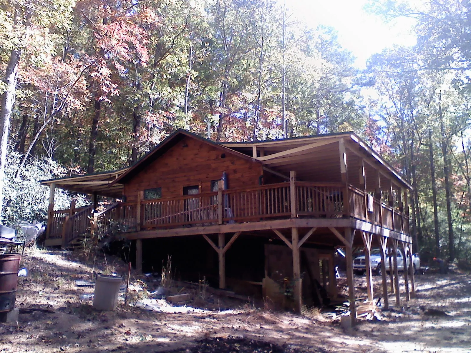 Log cabin with a wraparound porch and metal roof in the fall in Oregonia