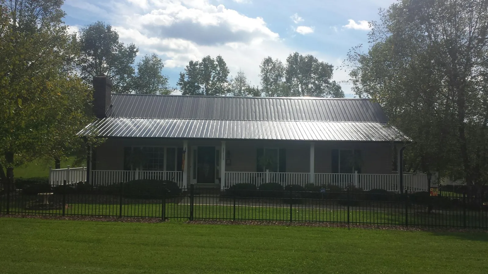 Gray metal roof on a brick ranch with a full width front porch — Gutter Guard Installation work by our crew in Oregonia