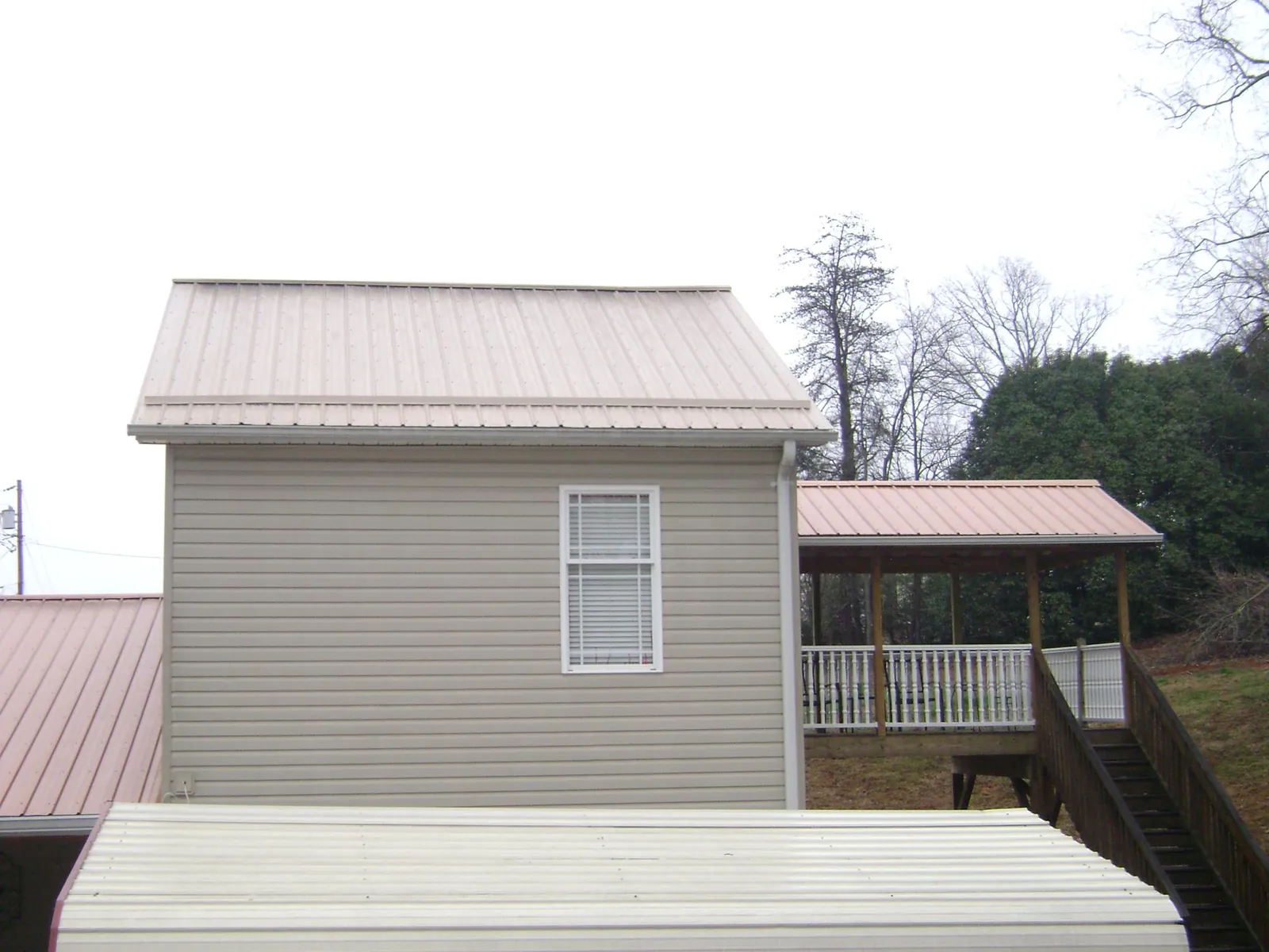 Tan metal roofs on a two story addition and attached porch, from a Roof Replacement job in Oregonia