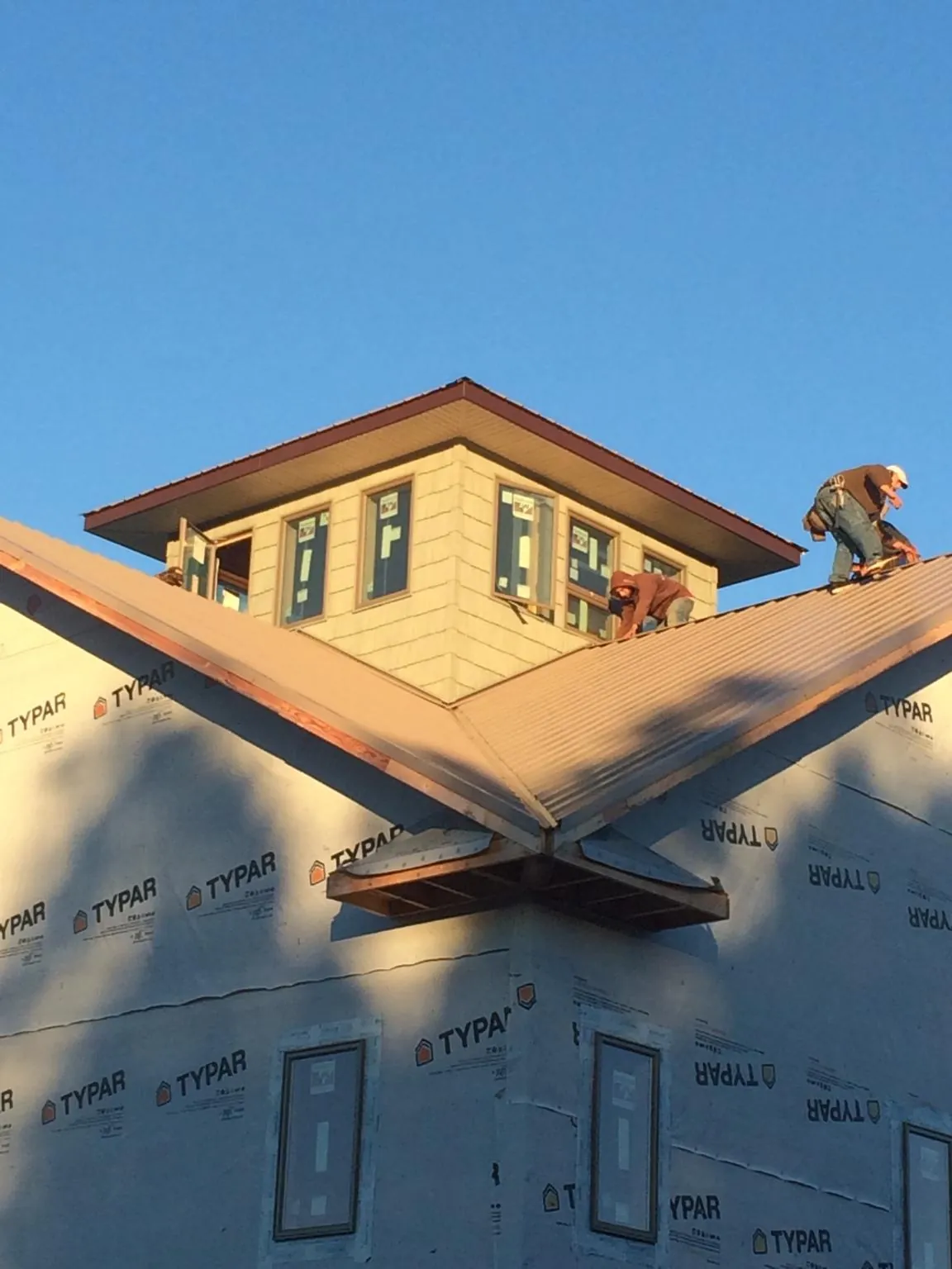 Roofers working around a rooftop cupola on a new metal roof at sunset — Roof Waterproofing in Oregonia by Roofing Brothers